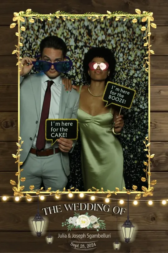 Couple in giant sunglasses with I’m Here for the Cake signs at a Hamilton wedding photo booth