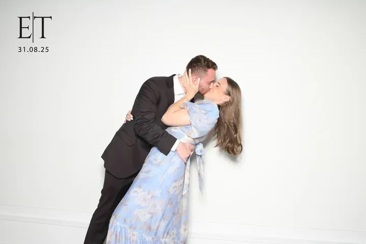 Couple kissing in the wedding photo booth on a white backdrop