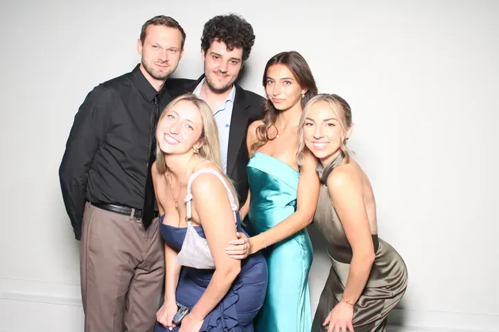 Five wedding guests posing at the photo booth on a white backdrop