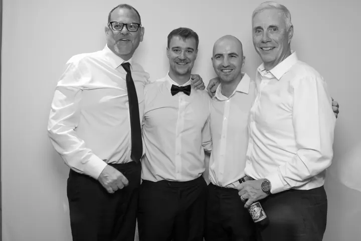 Four men in white shirts arm in arm at a St. Catharines wedding photo booth