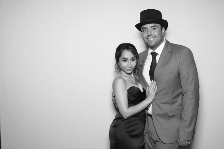 Black and white photo booth picture of a wedding couple, him in a top hat