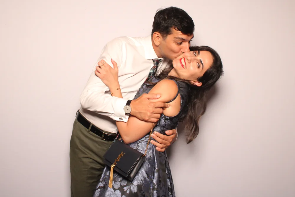 Guest kissing his partner on the cheek in a wedding photo booth