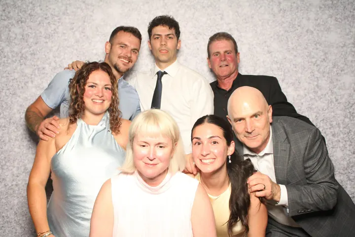 Family of seven at a wedding photo booth on a silver glitter backdrop