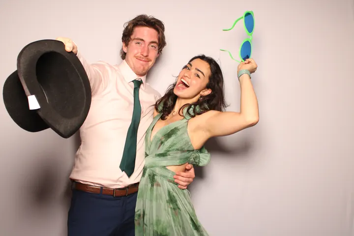 Wedding guests waving a top hat and giant sunglasses at the photo booth